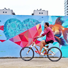 Boy on bicycle in front of urban mural